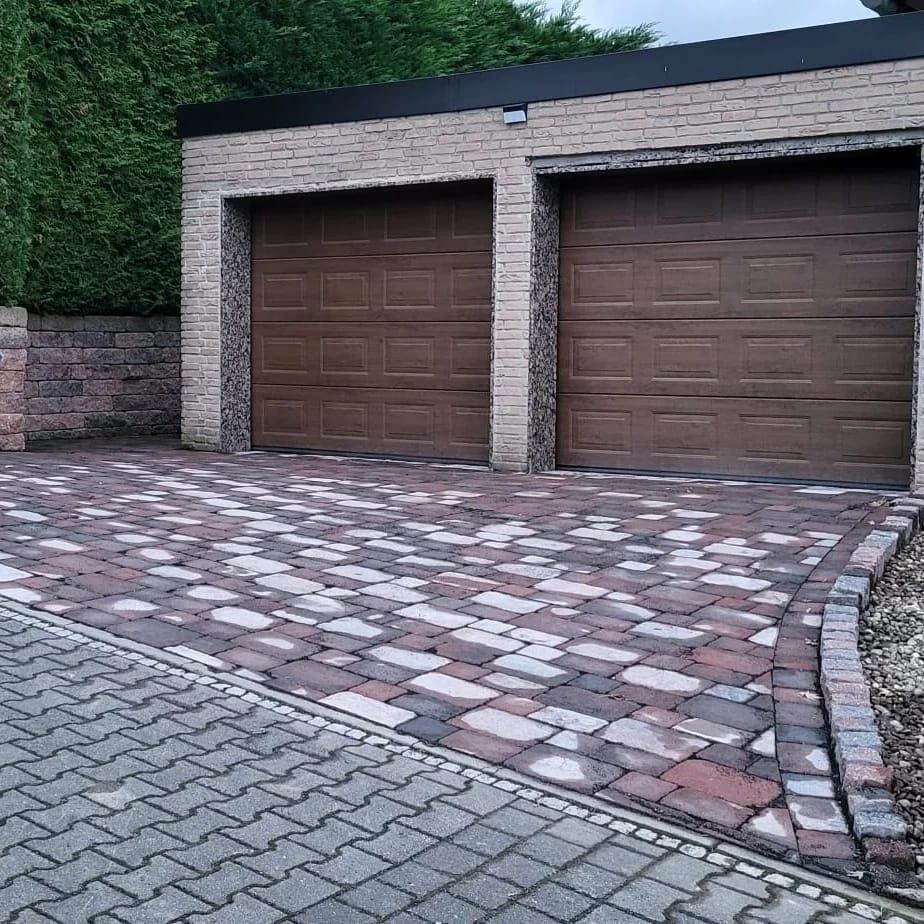 Pflasterarbeiten an einer Garageneinfahrt mit Palisaden als seitliche Stütze